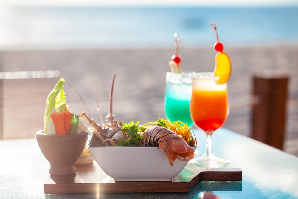 Lobster dish with colorful cocktails that go with seafood at an outdoor restaurant by the sea